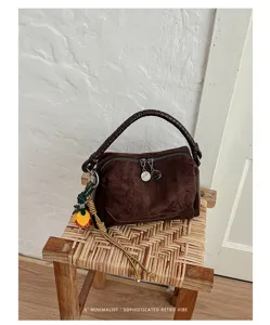 Vista detallada del bolso retro de ante marrón con asa trenzada y colgante de borla elegante.