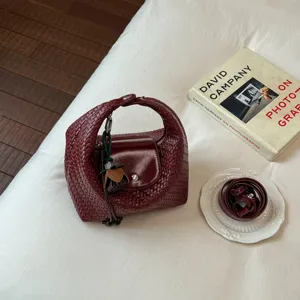 Woven leather hobo shoulder bag for women, chic dumpling handbag with strap and charm.
