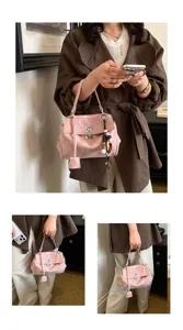 Modische rosafarbene Damen Handtasche mit elegantem Metallverschluss und Perlenanhänger.