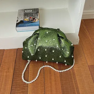 Detailed view of green glossy shell evening bag with pearl embellishments and beaded chain.