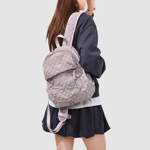 Vue détaillée du sac à dos de voyage décontracté gris à pois avec sa poche zippée.