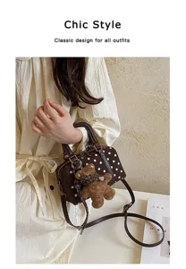 Detailed view of the brown polka dot boston bag with cute teddy bear charm and strap.