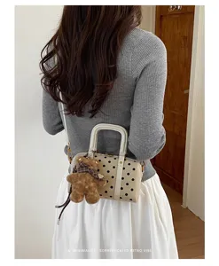 Vue détaillée du sac à main boston à pois élégant avec un joli accessoire pendentif en peluche.