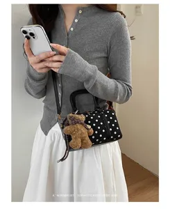 Chic black and white polka dot boston bag styled with teddy bear charm in daily outfit scene.