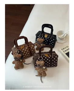 Polka dot Boston handbag detail view, elegant retro style with cute bear charm and handles.