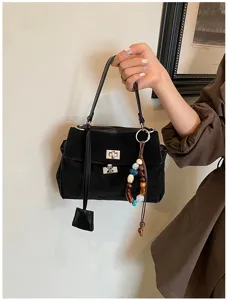 Schwarze Henkeltasche aus Wildleder mit elegantem Drehverschluss und bunten Perlenanhängern.