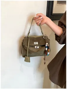 Grüne Wildleder Handtasche Detail mit Drehverschluss und Perlen Anhänger in schicker Szene.