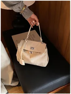 Beigefarbene Handtasche aus Wildleder mit Drehverschluss, ideal für elegante Damen im Alltag.