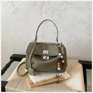 Olivenfarbene Wildleder Handtasche Detail mit doppelten Drehverschlüssen und Perlen.