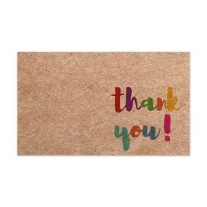 Primo piano biglietto ringraziamento carta kraft con tipografia colorata e superficie scrivibile.