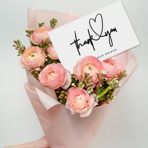 Detailed close-up of a white paper thank you card with elegant script for gift packaging.