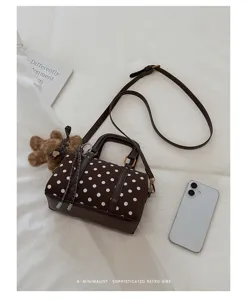 Chic brown polka dot Boston bag with crossbody strap and cute bear pendant for daily commute.
