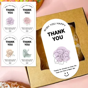Detalle de pegatinas de agradecimiento ovales con patrones florales y caja de regalo.