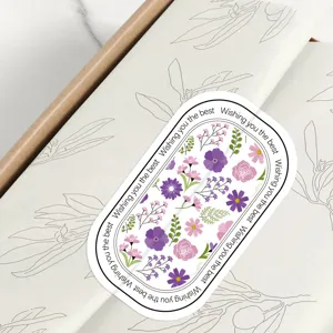 Nahaufnahme von ovalem Blumen-Deko-Aufkleber mit lila und rosa Blüten für Geschenkschachtel.
