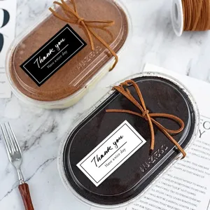 Detail view of baking thank you stickers on dessert packaging boxes with elegant ribbons.