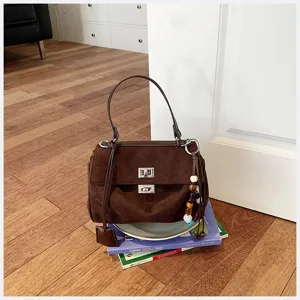Braune Wildleder-Henkeltasche mit Metalldrehverschluss, klassisches Retro-Design.