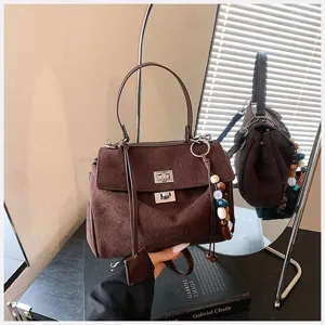 Detailansicht der stilvollen braunen Wildleder Henkeltasche mit elegantem Metallschloss.