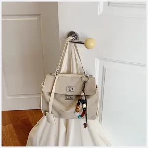 Beige Segeltuch Schultertasche Detail, elegantes Drehschloss und schickes Perlen Anhänger.