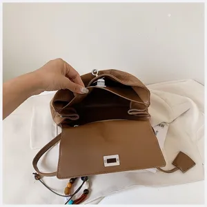 Braunes Wildleder Handtasche Innenansicht Detail mit Fächern und Metall Drehverschluss Design.