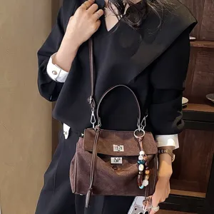 Braune Wildleder Handtasche für Damen, stilvolle Umhängetasche mit Henkel und schickem Perlenanhänger.