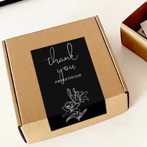 Close-up detail of black rectangular thank you sealing sticker with white floral line art.
