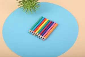 Gros plan de crayons de couleur en bois joliment disposés sur un tapis rond bleu vif.