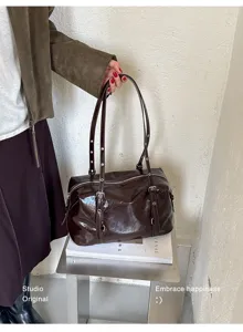 Vue rapprochée détaillée de l'élégant sac bandoulière Boston en cuir verni marron.