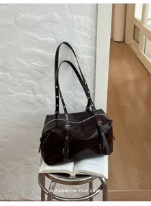 Détail élégant du sac à bandoulière en cuir verni marron foncé avec superbes brides à œillets.