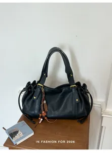 Detailansicht der schwarzen Lederschultertasche mit stilvollen Metallbeschlägen und Quasten.