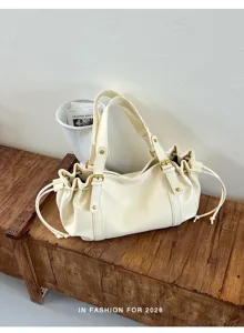 Cremeweiße slouchy Schultertasche Detail mit weichem Leder und Schnallen auf Holzbank.
