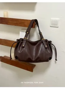 Retro braune slouchy Schultertasche mit Schnallen- und Kordelzugdetails, stylische Tote.