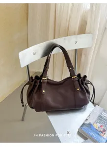 Detailansicht der dunkelbraunen Schultertasche aus Leder auf modernem Stuhl im Raum.