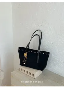 Détail de sac cabas en suédine noire, sac porté épaule rétro avec rivets et charm fleur.