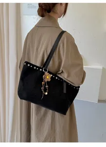 Sac cabas élégant en suédine noire pour femme avec rivets métalliques et pendentif.