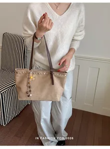 Vue détaillée du sac cabas rétro avec rivets décoratifs et charmant pendentif de pampille florale.