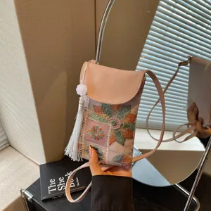 Close-up detail of the ethnic embroidered pink mini crossbody phone bag with white tassel.