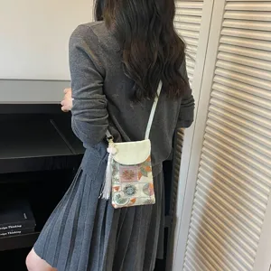Detail view of Chinese style embroidered crossbody phone bag with tassel and shoulder strap.