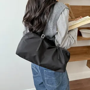 Schwarze Nylon-Schultertasche im Detail mit minimalistischem Design und feinen Riemen.