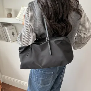 Detailaufnahme der stilvollen schwarzen Nylon Schultertasche in lässiger Lifestyle Szene.