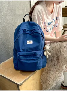 Detailansicht des blauen Rucksacks mit robustem Stoff, Fronttasche und süßem Anhänger.