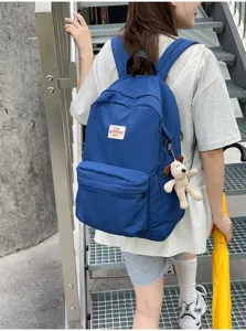 Detailansicht des blauen Canvas-Rucksacks für Damen mit Vordertasche und süßem Hundeanhänger.