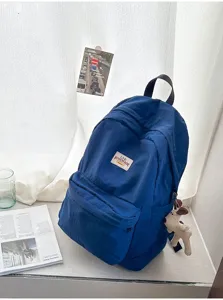 Detailansicht des lässigen blauen Segeltuch-Rucksacks mit süßem Plüsch-Anhänger am Tisch.