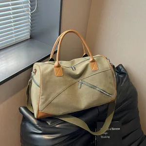 Détail de sac de voyage en toile avec poche zippée diagonale et poignées en cuir marron.