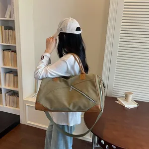 Vue détaillée d'un grand sac de voyage en toile avec garniture en cuir porté par le modèle.