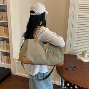 Détail de grand sac de voyage en toile avec garnitures en cuir marron et sangle.
