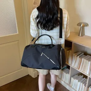 Vue détaillée d'un grand sac de voyage en toile noire avec bandoulière et poche zippée.