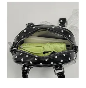 Detail shot of black polka dot handbag interior capacity showing phone and umbrella storage.