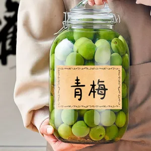 Bocal de stockage en verre transparent rempli de prunes vertes fraiches avec etiquette.