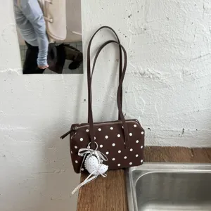 Detalle de bolso de boliche de lunares marrón con textura de tela, cremallera y abalorio.