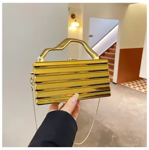Borsa a tracolla rigida metallica dorata da sera con manico geometrico e catena chic.